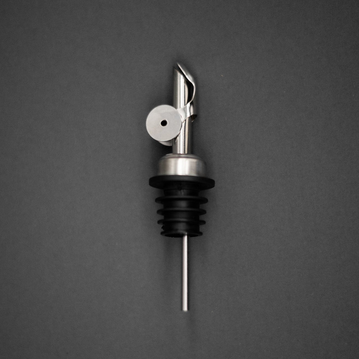 Metallic olive oil bottle pourer on a dark gray background