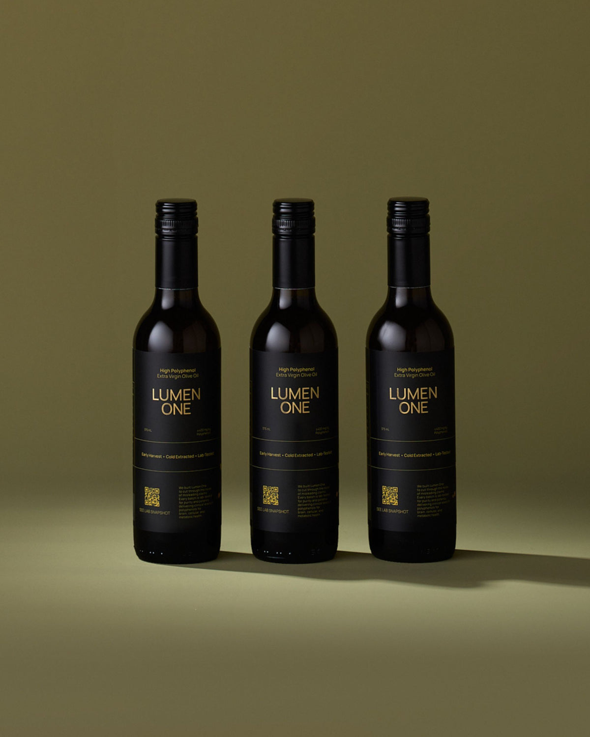Three bottles of Lumen One extra virgin olive oil on an olive-green background